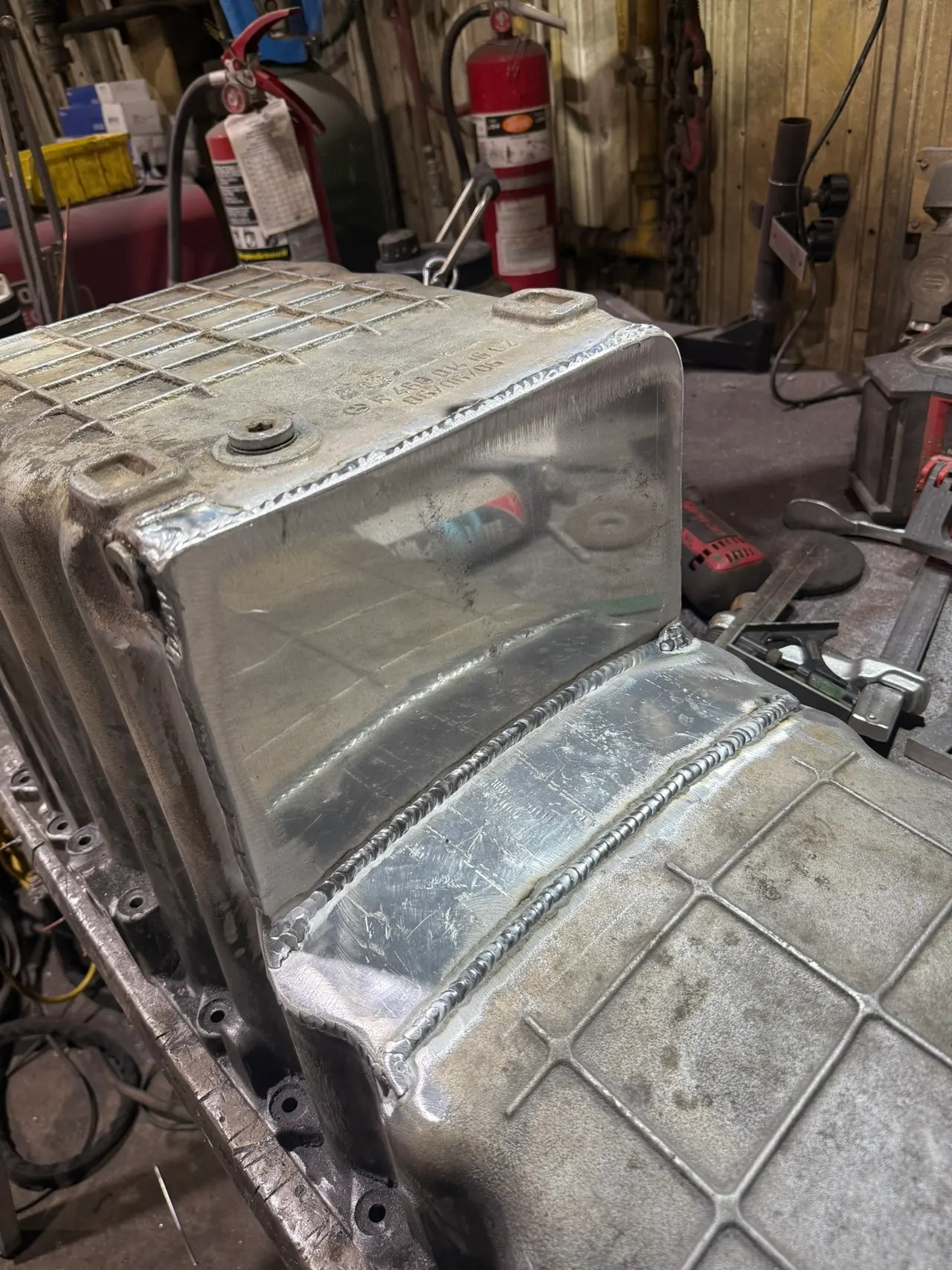 Fabricated aluminum tank with welded seams and a threaded fitting on the workbench