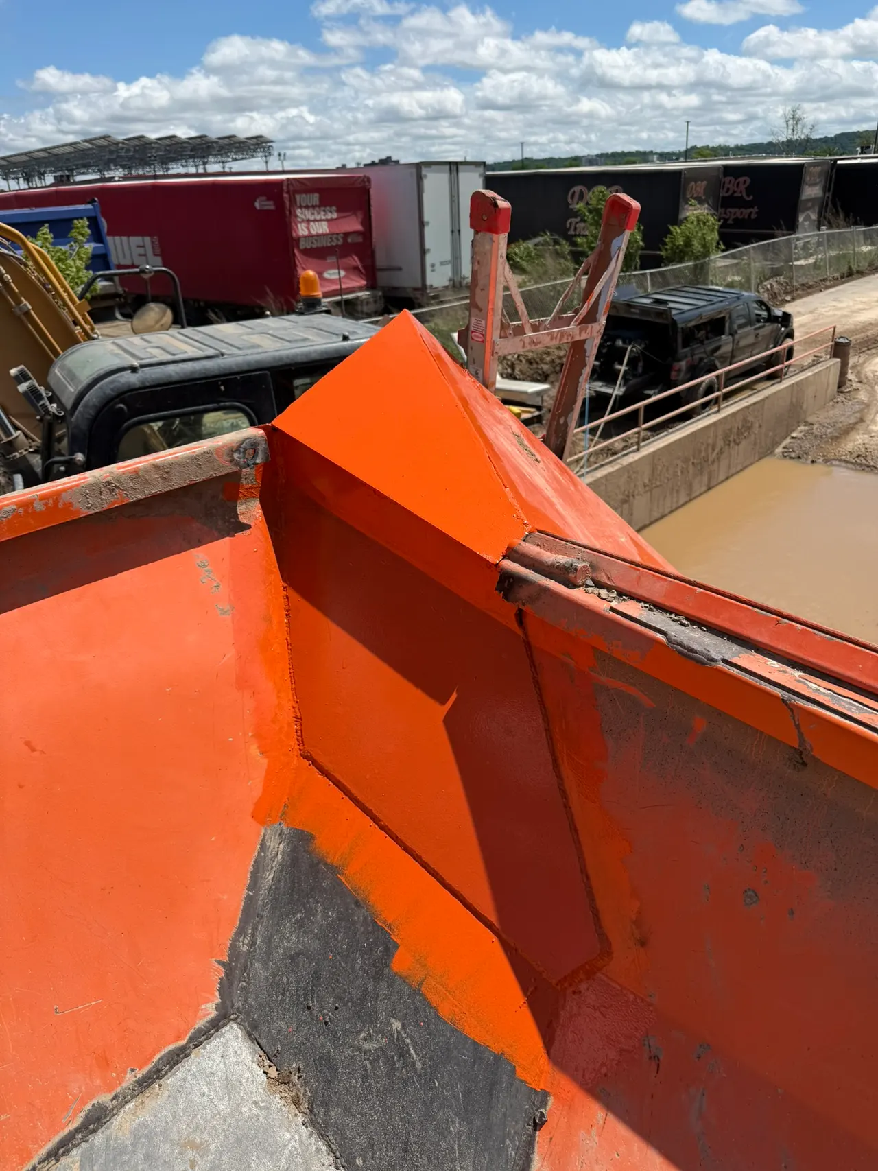 Orange fabricated drip ledge beside the washout pit and railings