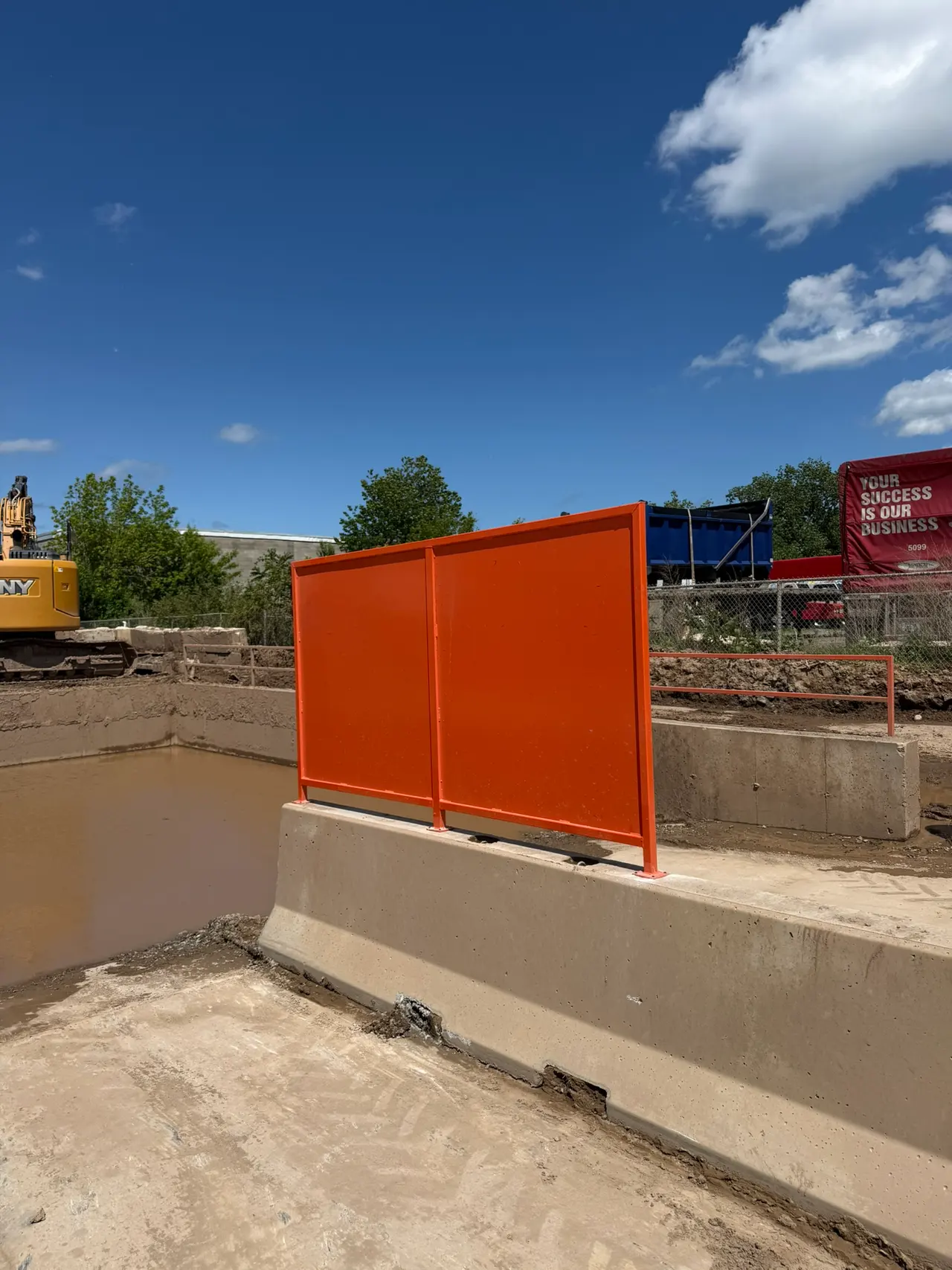 Bright orange splashguard wall separating two truck dumping lanes at the washout plant